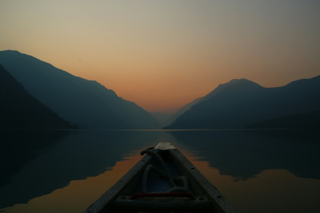 Traveller on a boat on a calm mountain lake at sunrise