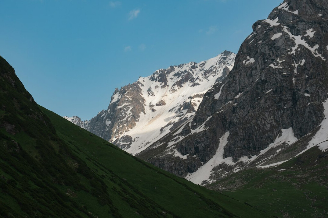 Snowy mountain peaks above a green valley at sunrise