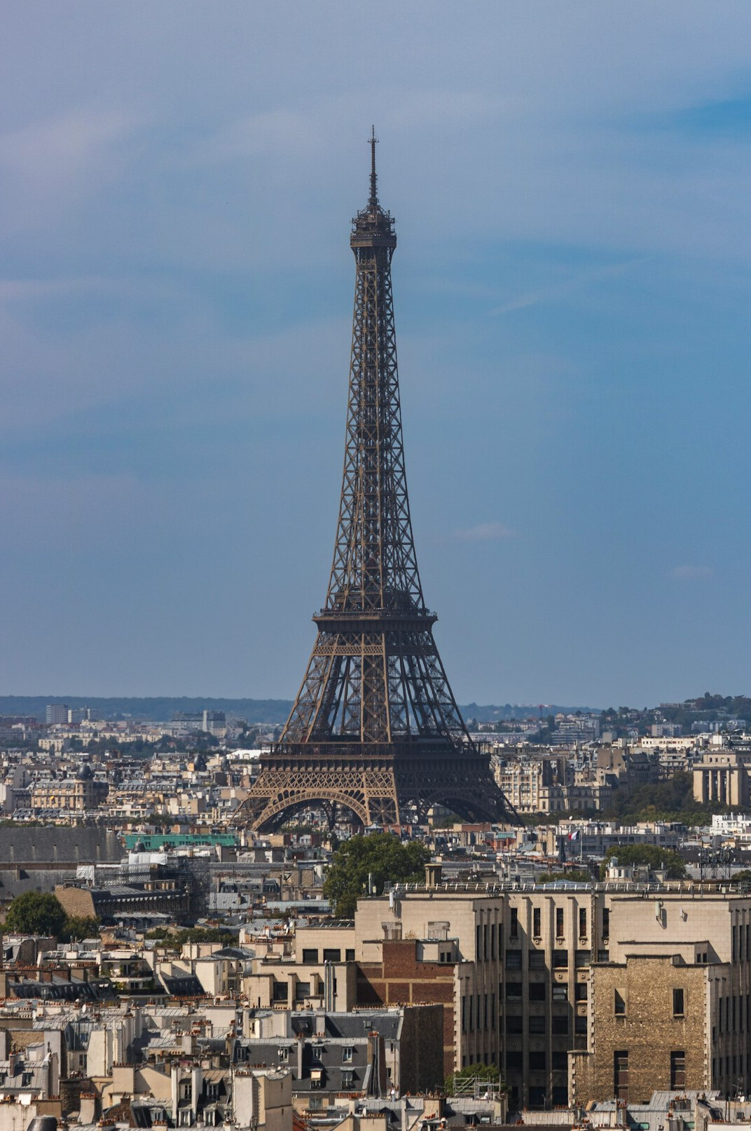 Eiffel Tower in Paris with a sunny sky and city rooftops